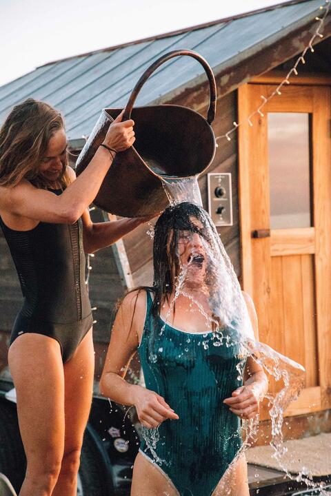 A woman douses another woman in cold water