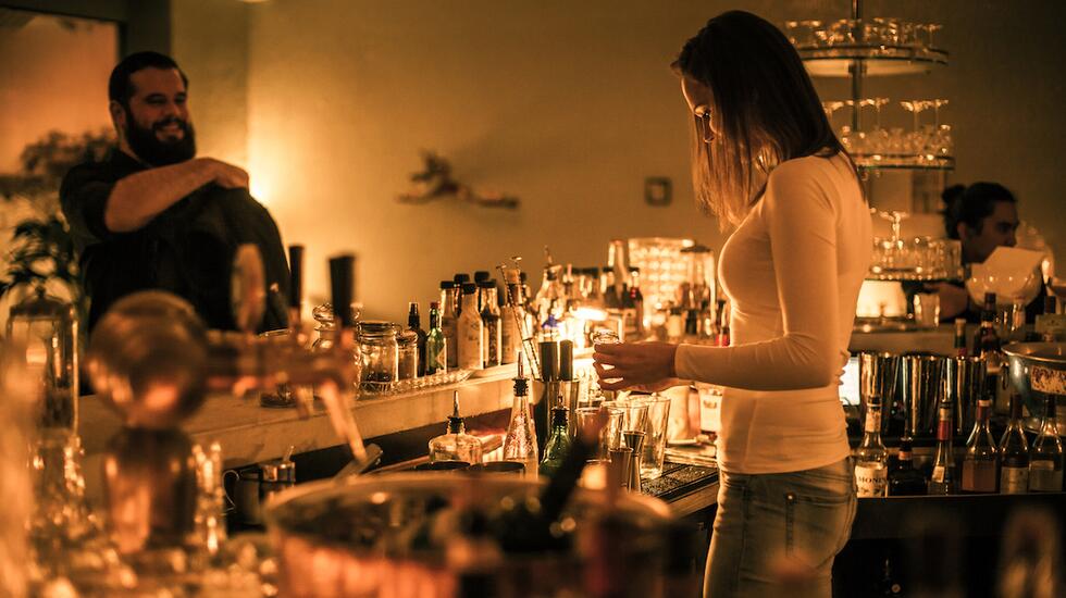 A woman tends the bar at cocktail spot Le Verre a Monique in Geneva